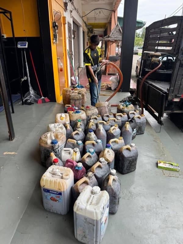 Botol minyak masak terpakai di hadapan pam dan tangki hitam di gudang