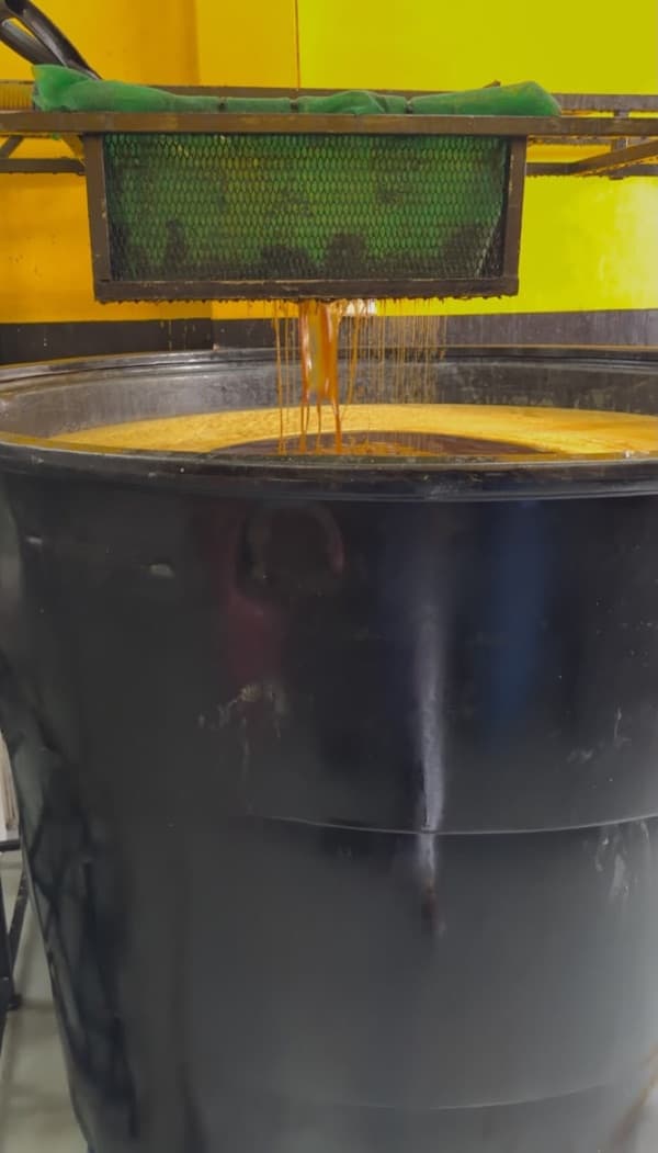 Minyak masak terpakai menitis melalui penapis jaring ke dalam tangki hitam