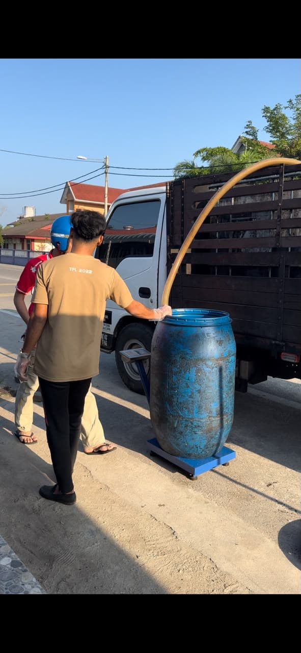 Staf MSR mengepam minyak masak terpakai dari tong biru di atas penimbang ke lori