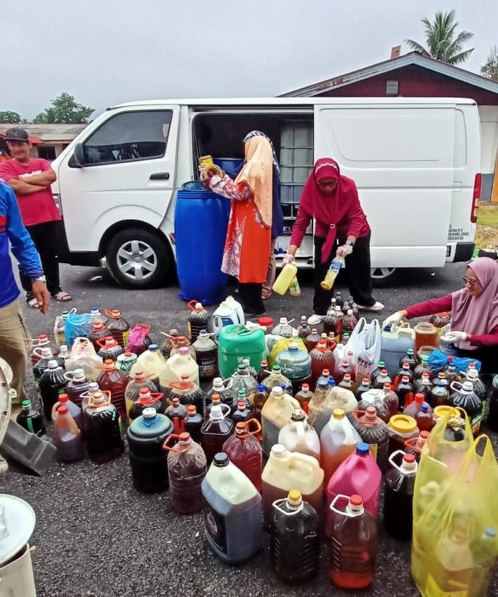 Van putih di lokasi kutipan dengan banyak botol dan tong minyak masak terpakai